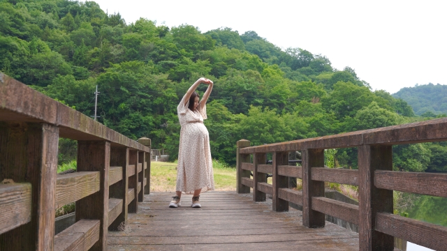 妊婦さんが公園で伸びをしている画像