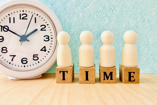 時計とTIMEのアルファベットに乗った人形