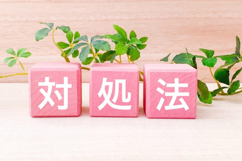 木目の背景に緑の植物とピンク色の木のブロックに対処法の文字の画像
