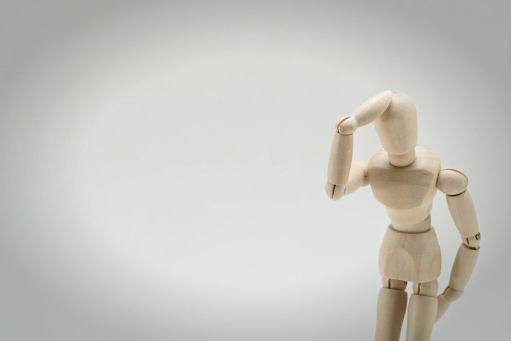 木製の人形右手を頭にあて困ったような様子の画像