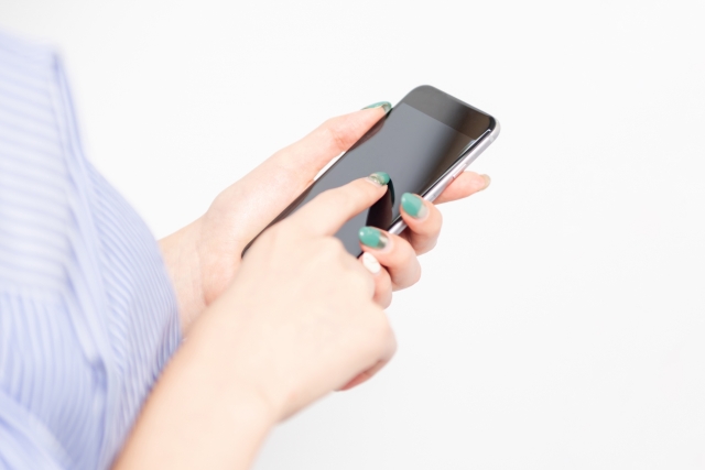 スマホを操作する女性の手の画像