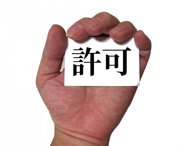 許可と書かれた紙を握っている手の画像