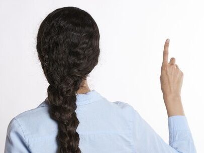 三つ編みをした髪の長い女性が、後ろ向きで右手で人差し指を指している画像