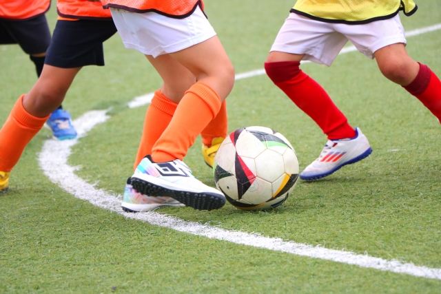 サッカーしている少年たちの足の画像