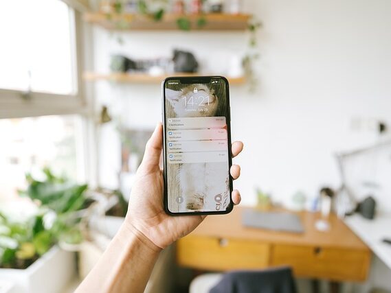 部屋の中で、左手でスマートフォンを持っている画像