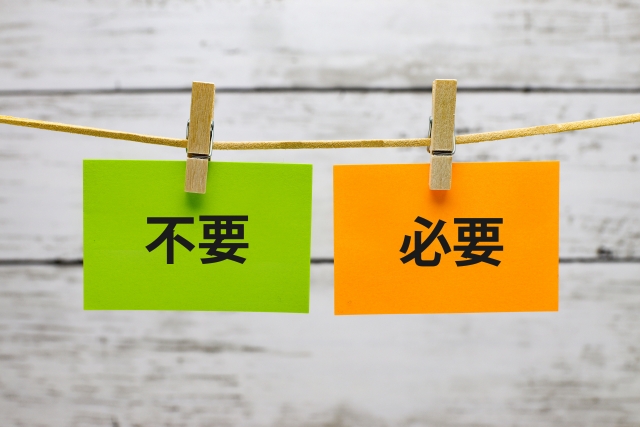 緑の紙に「不要」、オレンジの紙に「必要」と書かれたカードが木製ピンチで挟まれて一本の紐に吊るされている画像