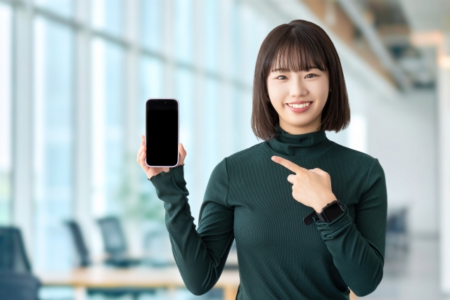 スマホを持って微笑む女性の画像
