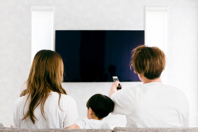 テレビを見ている家族の後ろ姿の画像