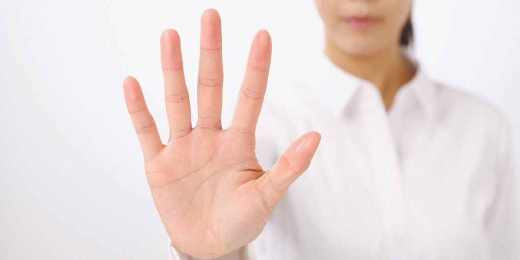 女性が手のひらをこちらに向けて拒否のジェスチャーをする画像