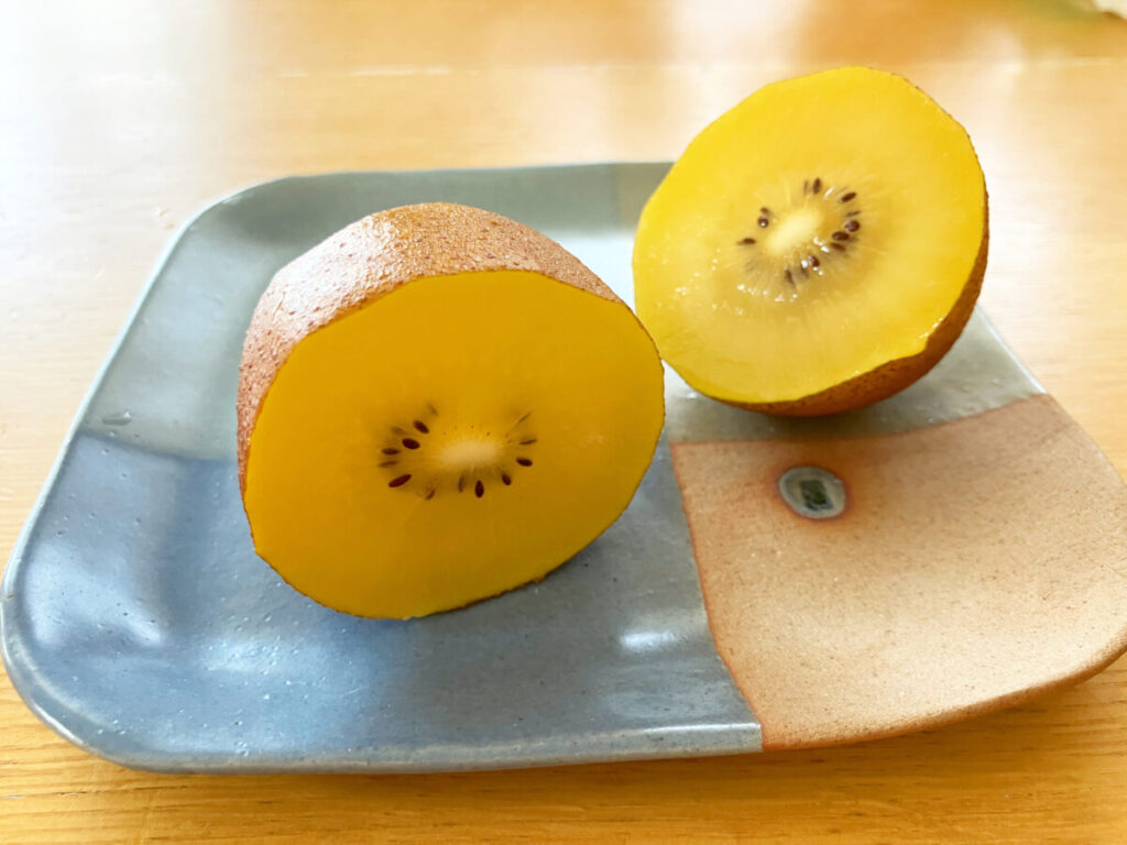 熟して食べ頃の半分にカットされたゴールドキウイの画像