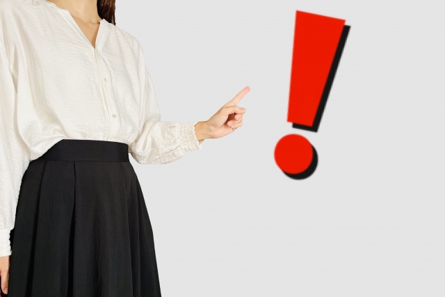 女性がビックリマークを指さしている画像