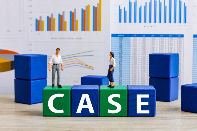 後ろには棒グラフ、前には「case」と書かれたブロックの上に、女性と男性のフィギュアがある画像