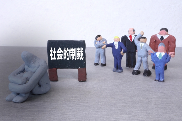 「社会的制裁」と書かれた看板の前に反省している粘土の人がいて、後にいろんなフィギュアが立っている画像